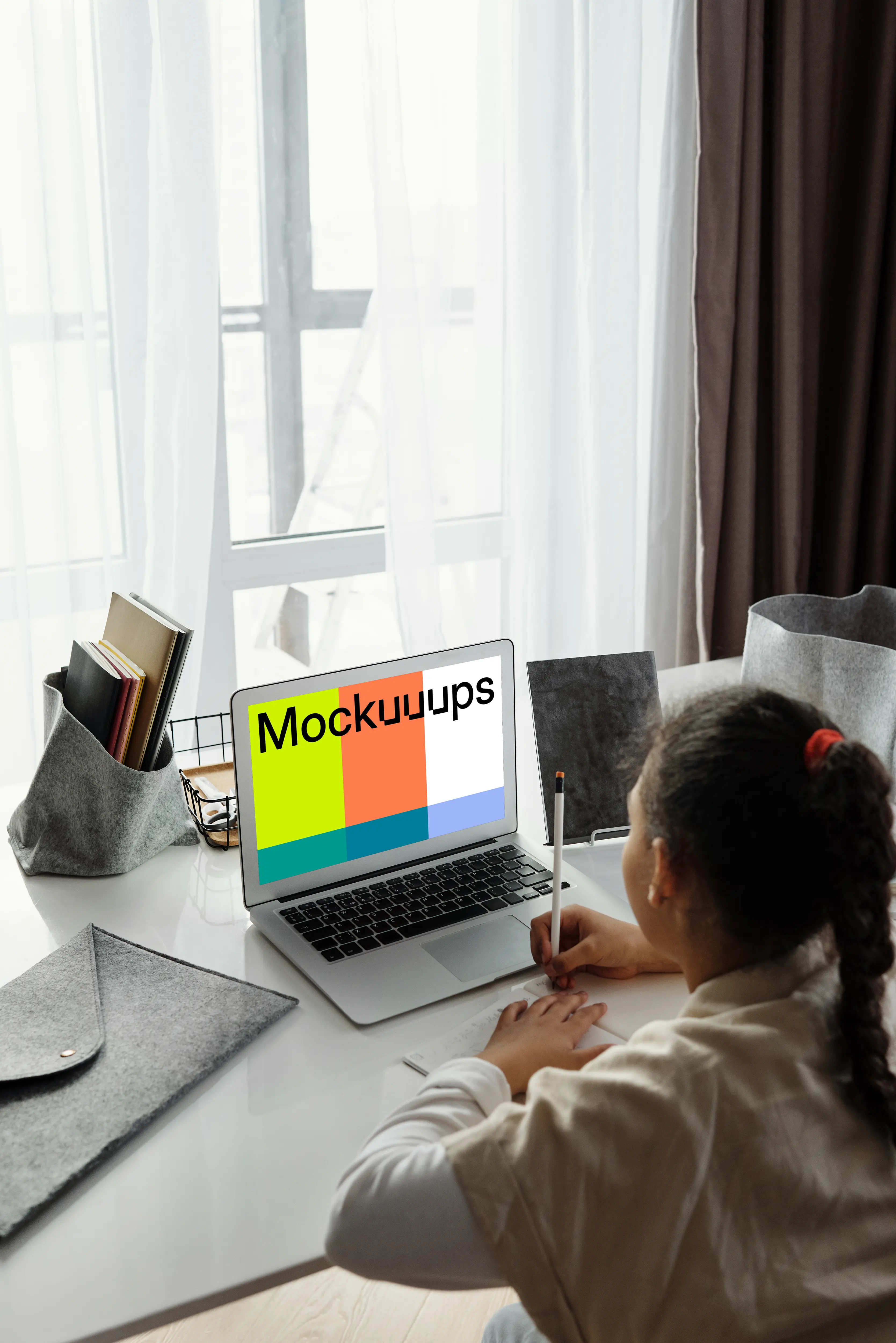 Mockup of Young girl viewing her MacBook Air screen and writing in a book