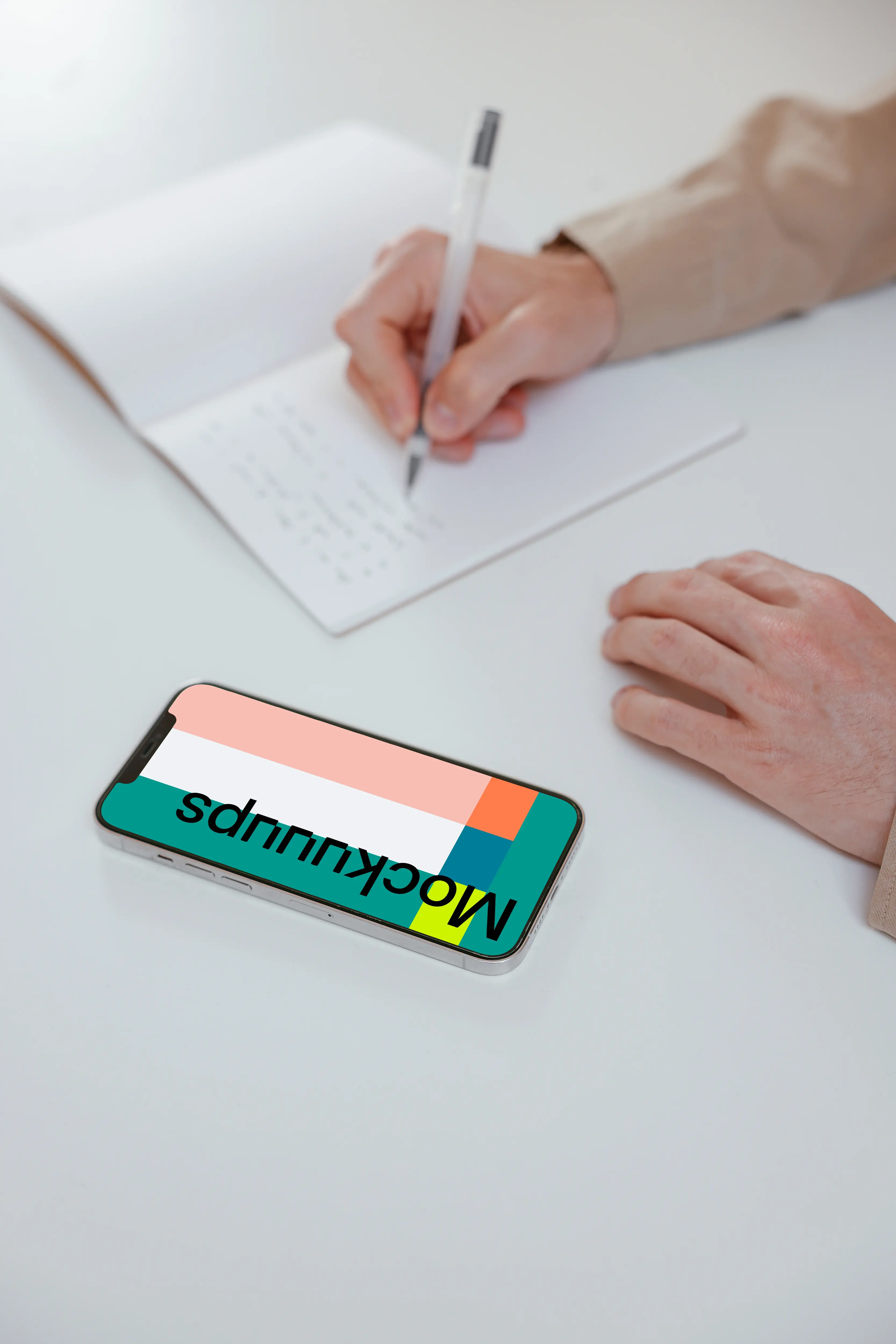 Simple iPhone mockup on a white table with a user writing by the side