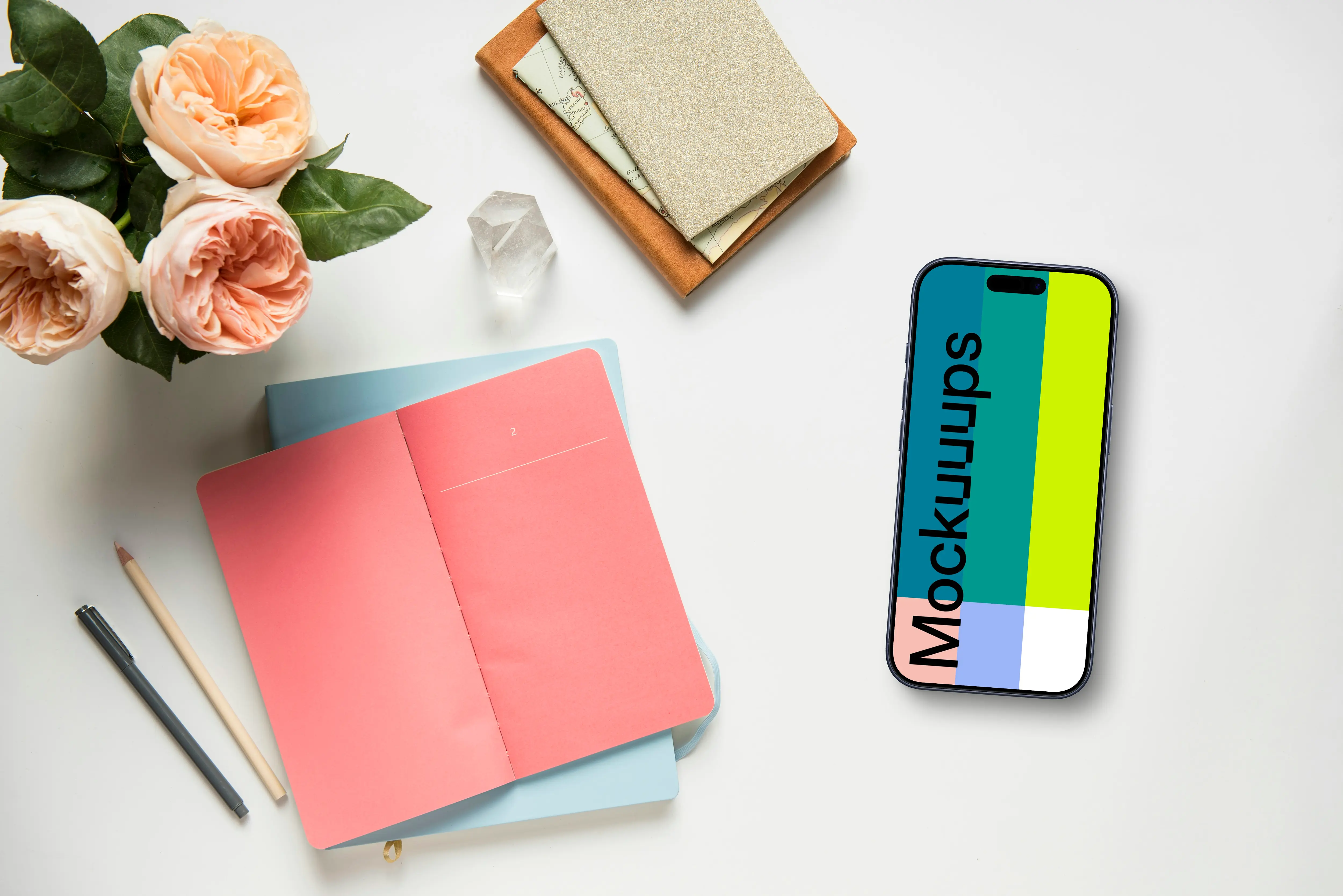 Smartphone mockup next to a pink notepad and flowers