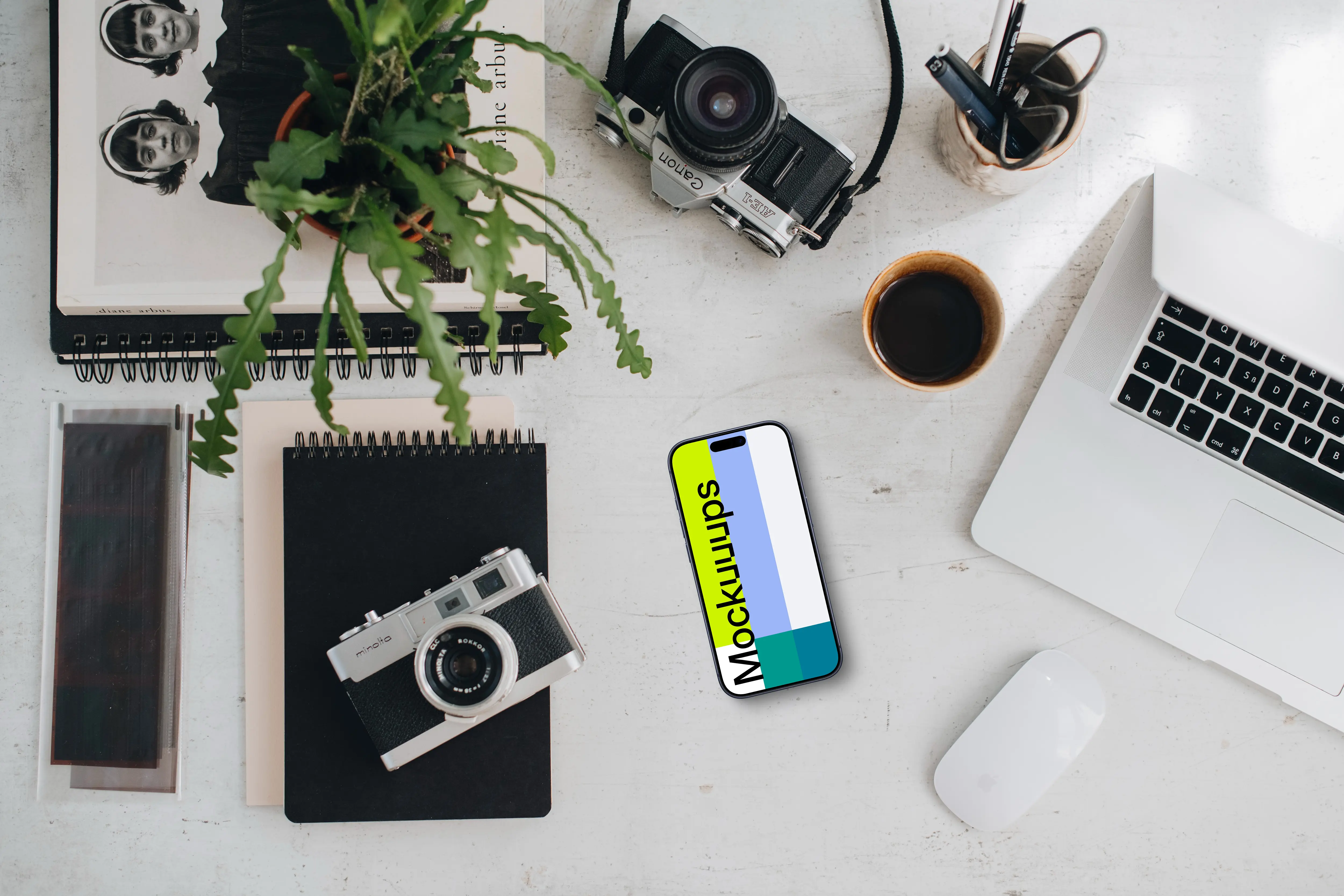 Top view of phone mockup with a MacBook Pro and camera on the side