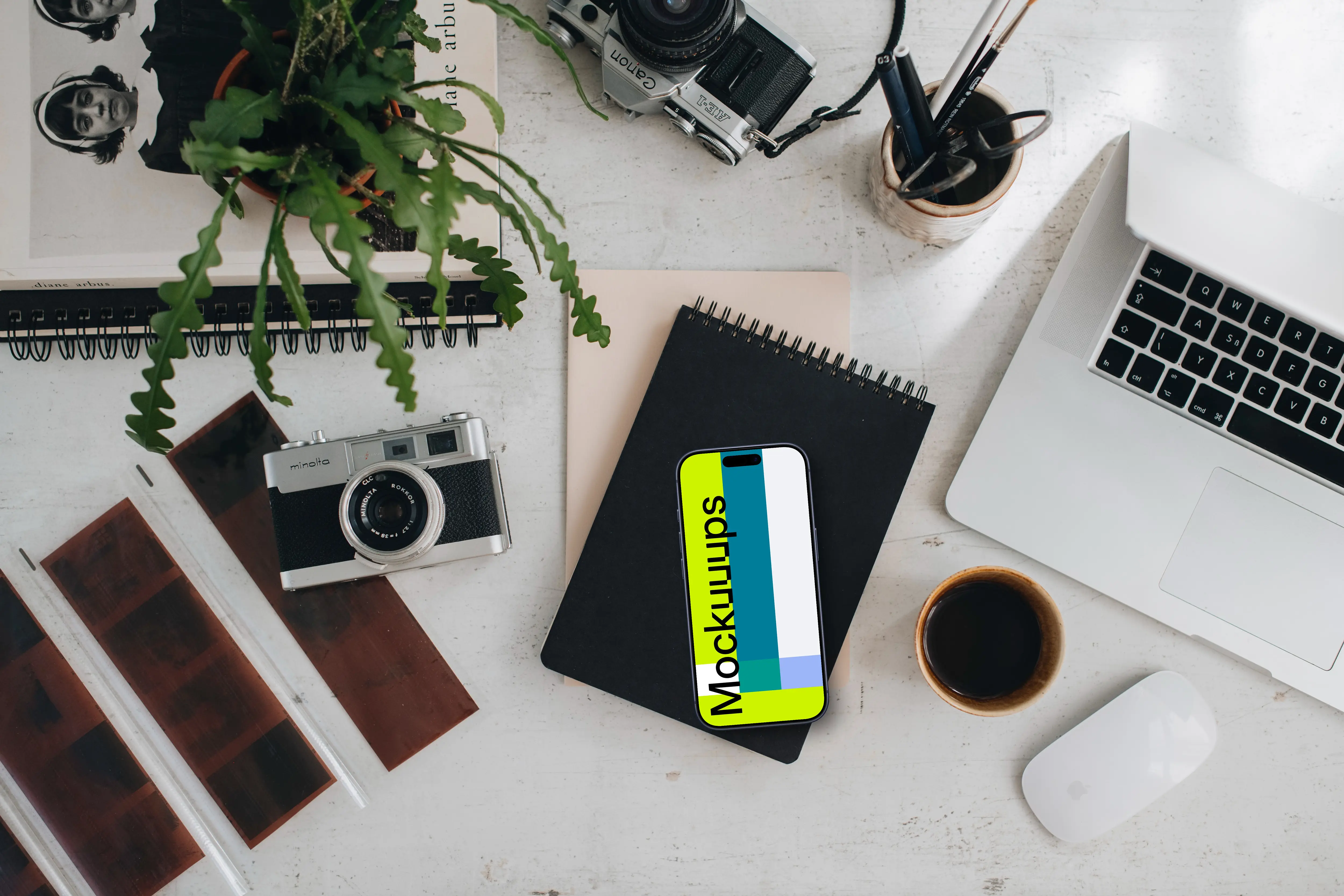 Top view of phone mockup with analog cameras and book