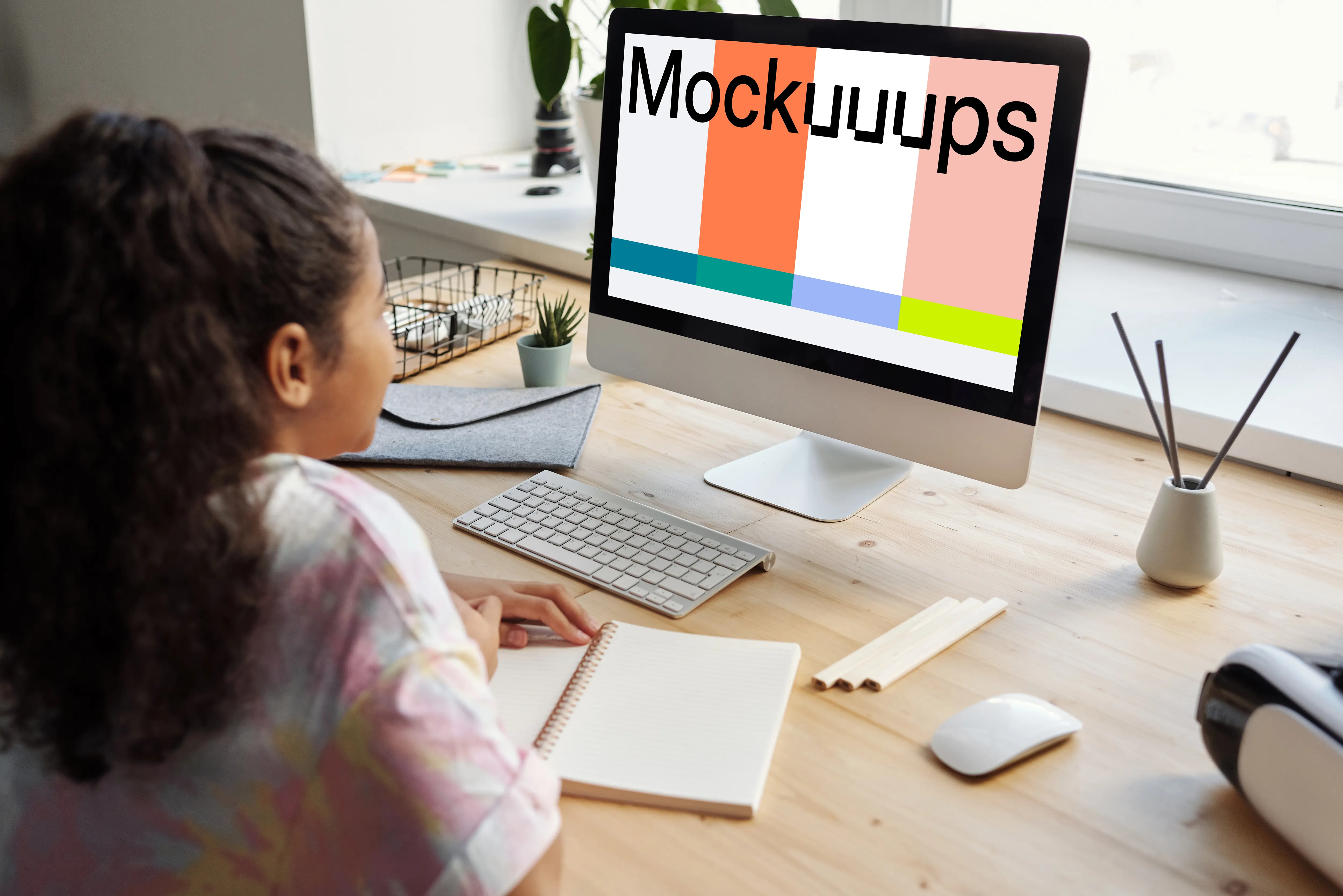 Young girl using an iMac with a book on the table