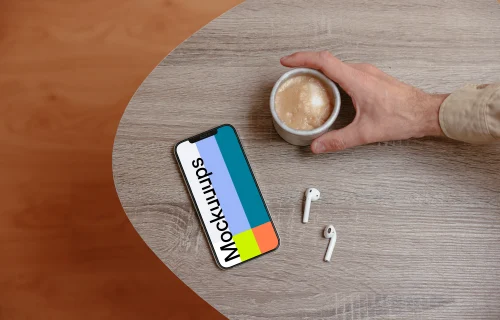 iPhone mockup on a wooden table next to a cup of coffee and a pair of AirPods.