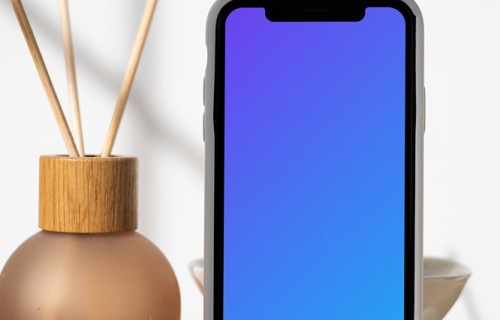 iPhone mockup standing vertically on a table next to a vase with empty sticks in them.