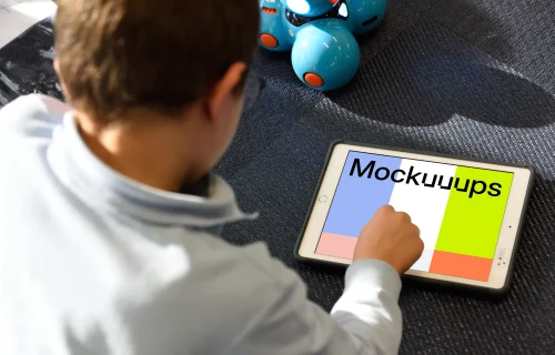Kid using an iPad mockup with a toy by the side