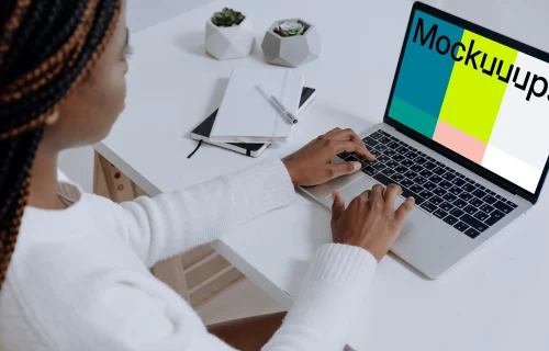 MacBook Pro on white table beside a notebook and pen