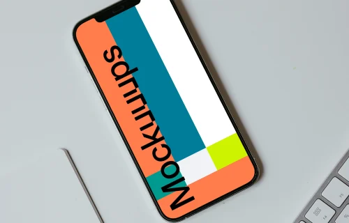 Minimal iPhone mockup on a white table with a wireless keyboard by the side