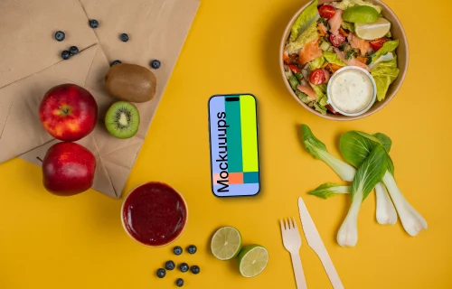 Smartphone mockup between fresh fruits and salad