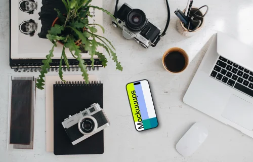 Top view of phone mockup with a MacBook Pro and camera on the side