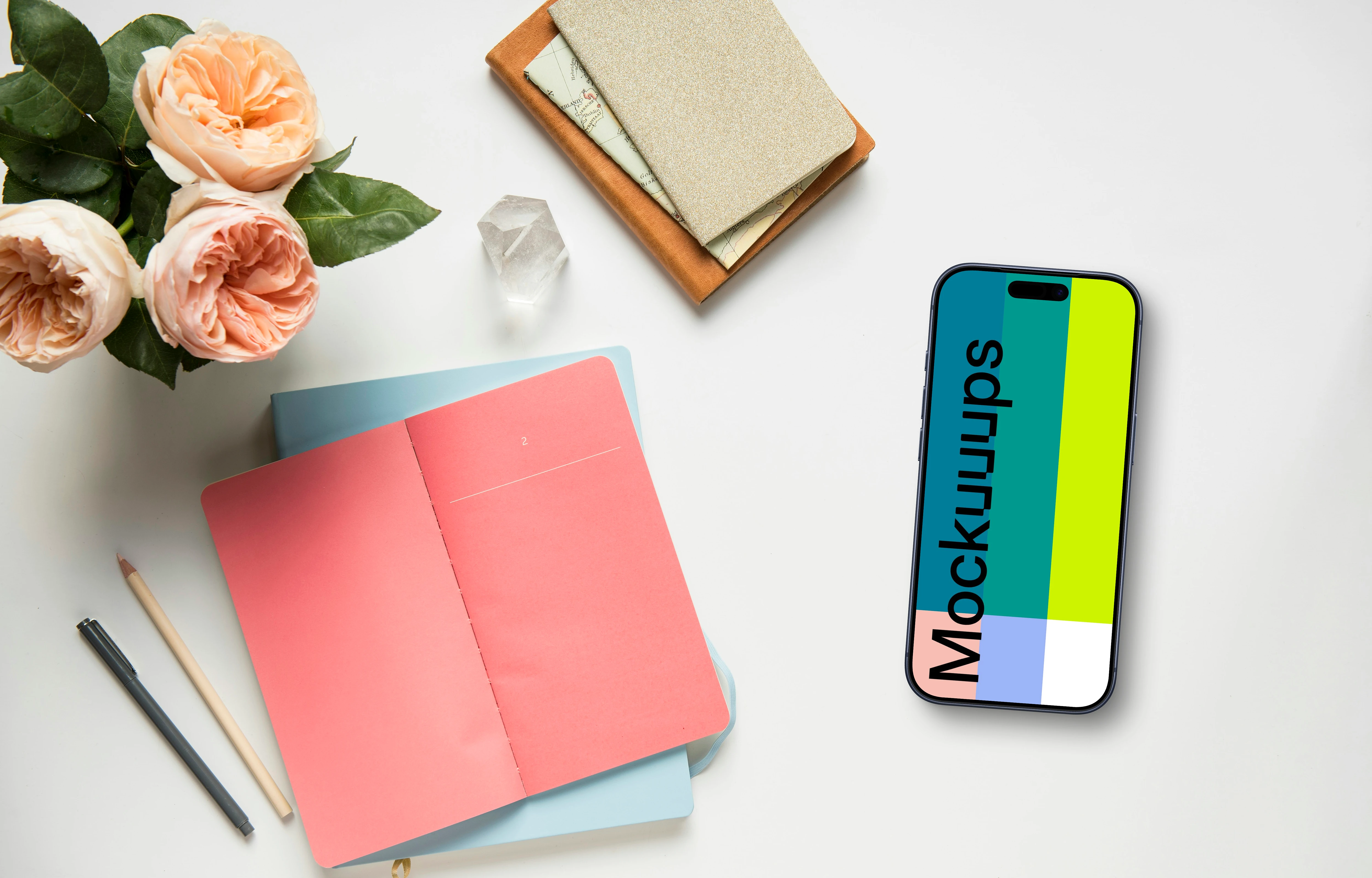 Smartphone mockup next to a pink notepad and flowers