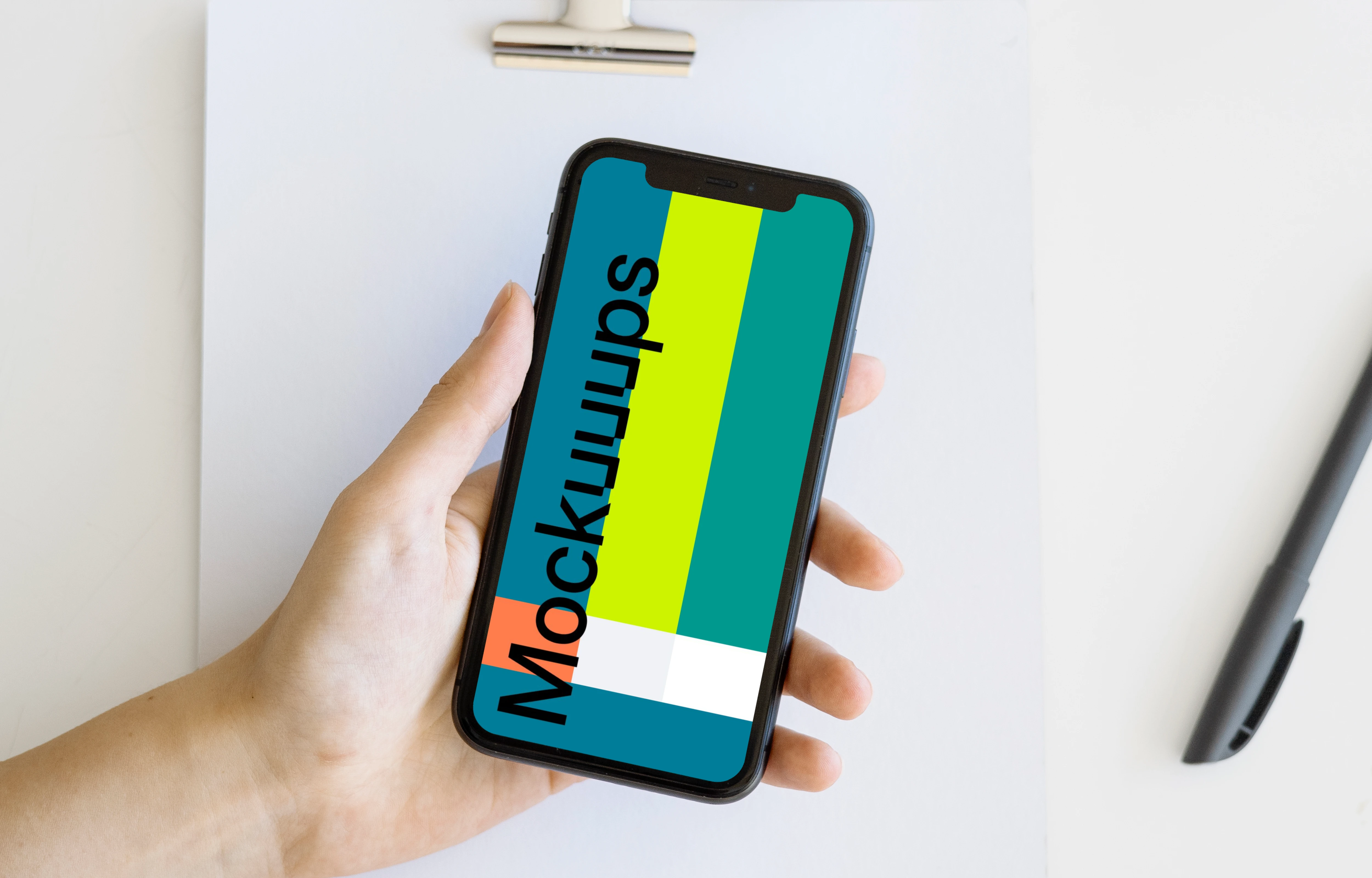 iPhone mockup in a user’s hand over a note pad and a cork