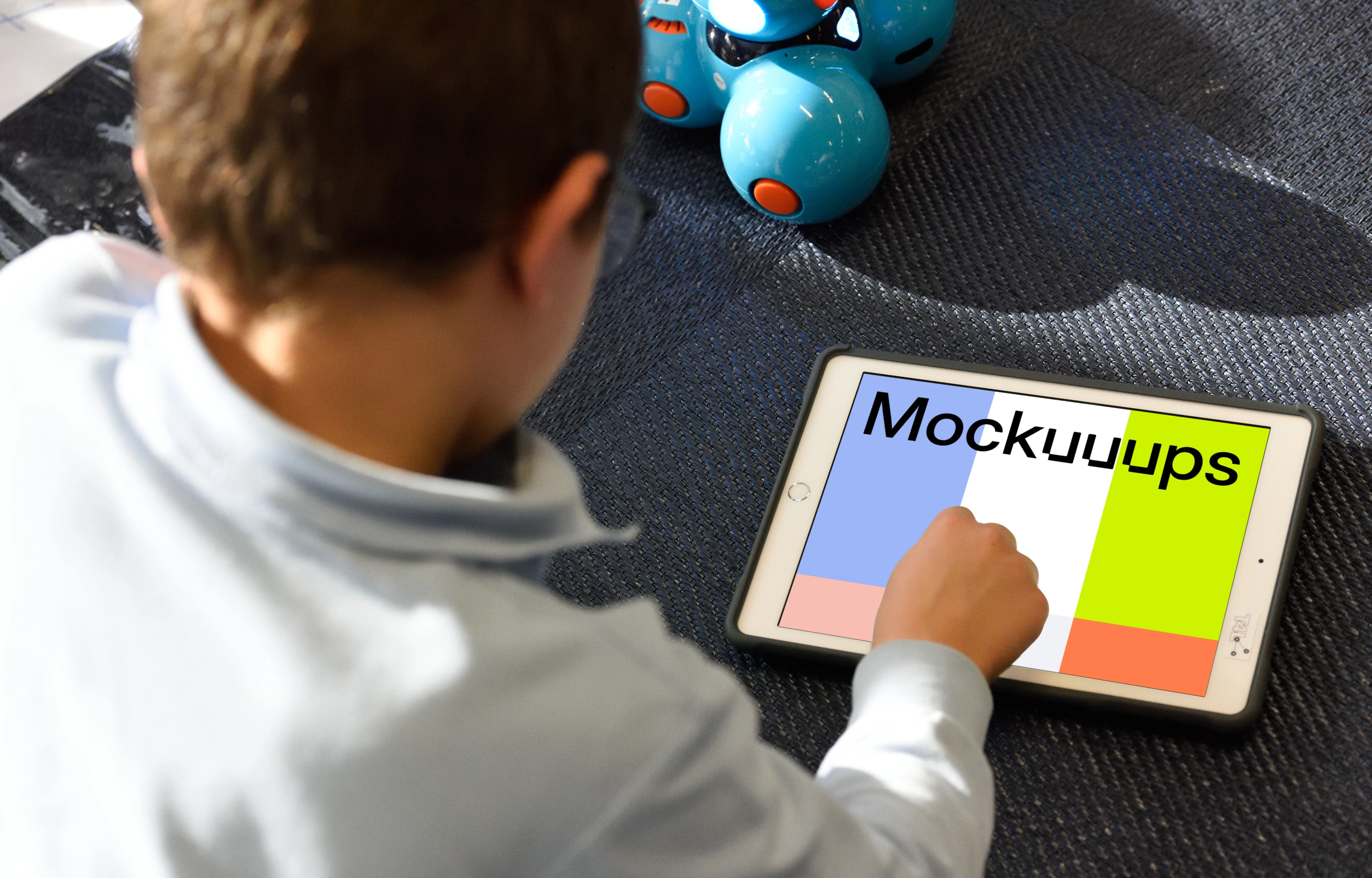 Kid using an iPad mockup with a toy by the side