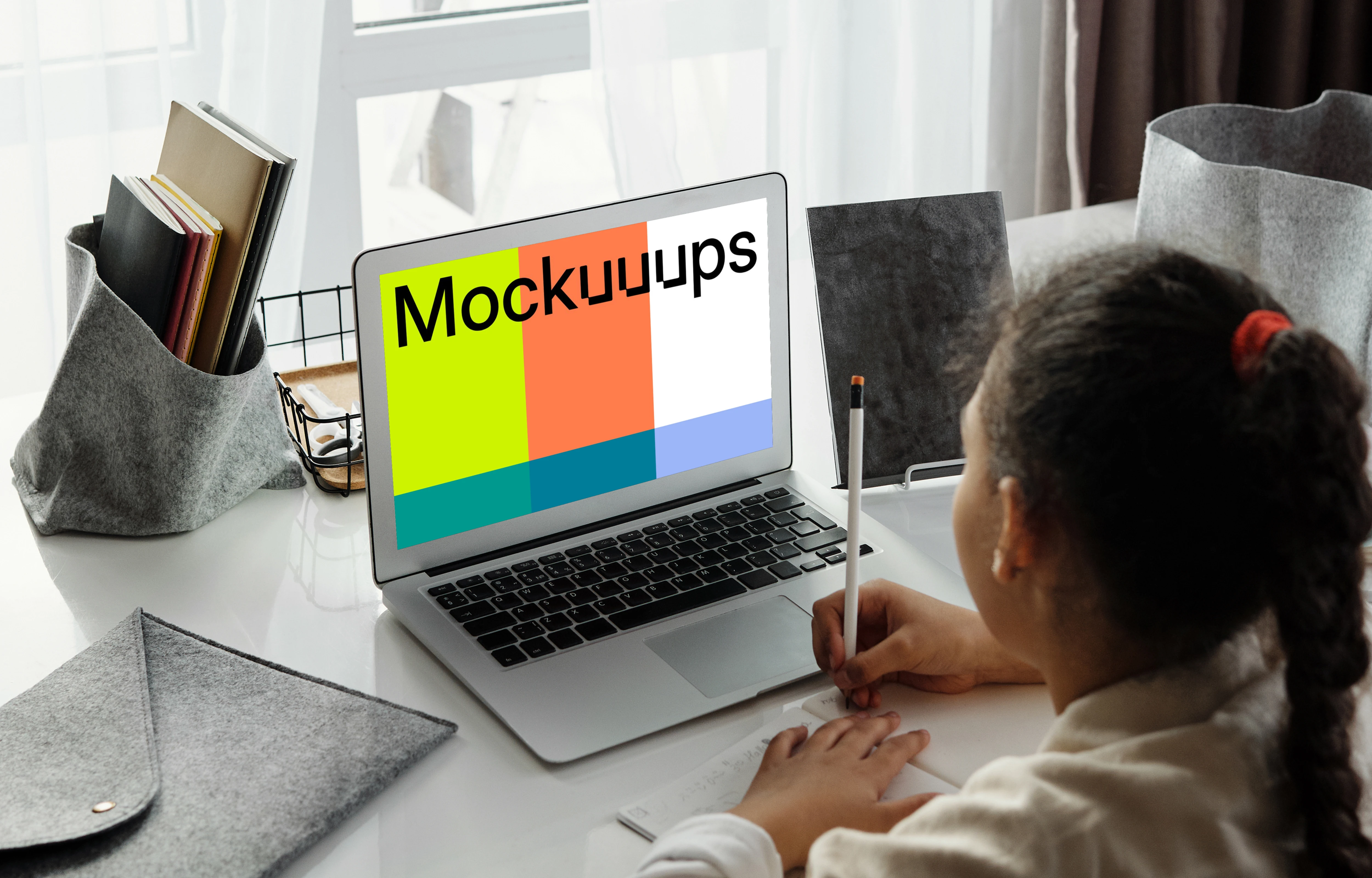 Mockup of Young girl viewing her MacBook Air screen and writing in a book