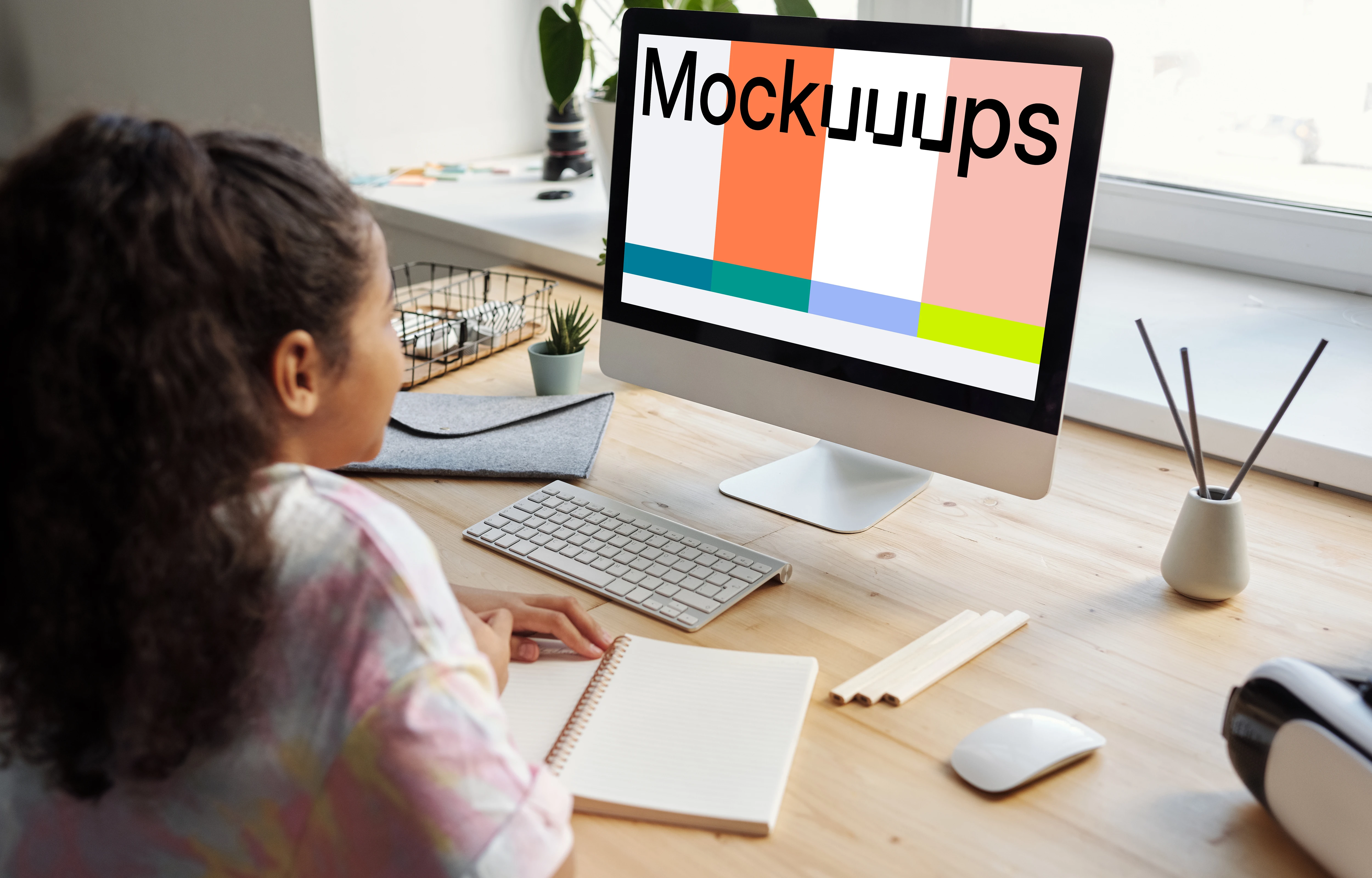 Young girl using an iMac with a book on the table