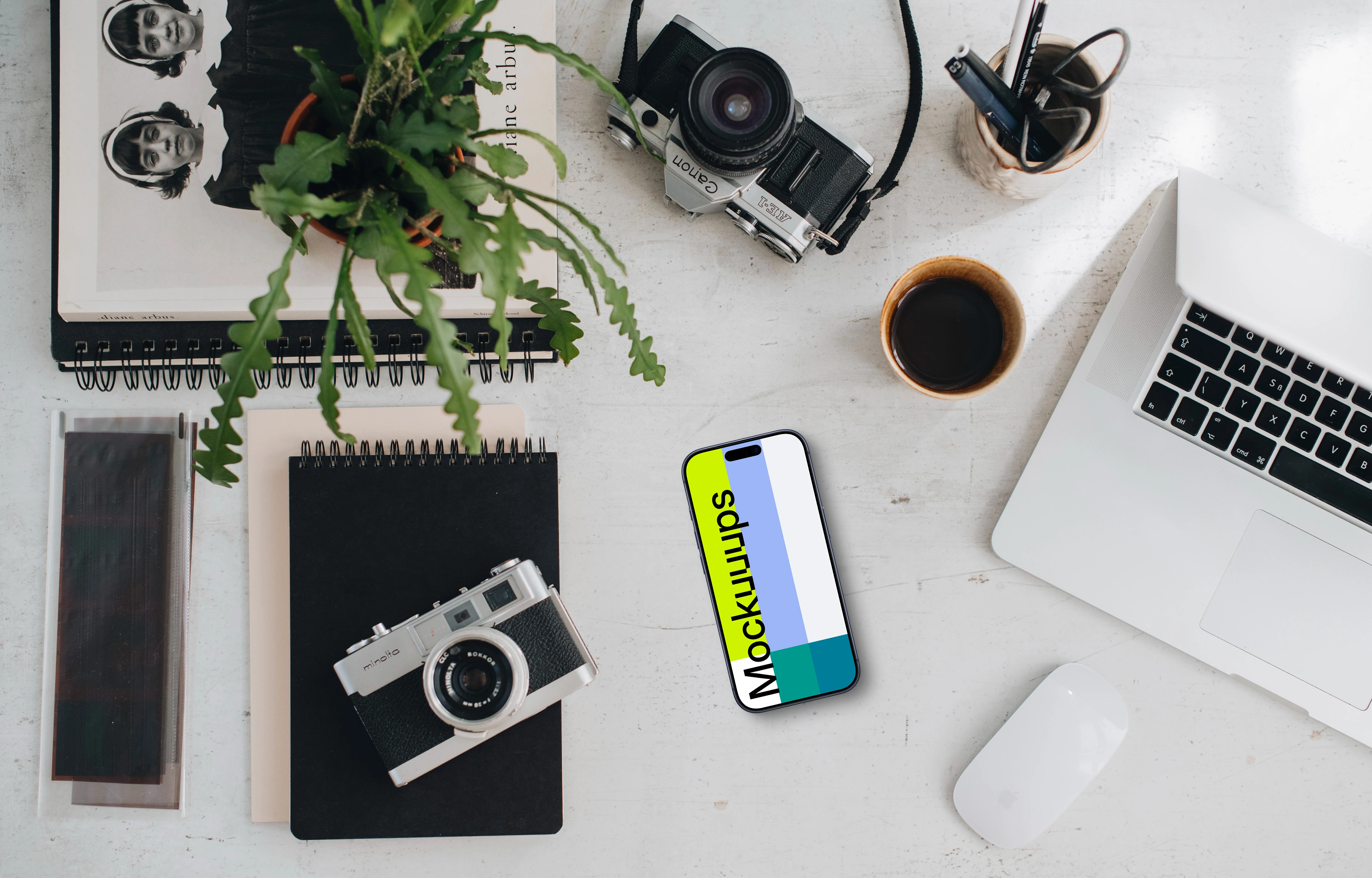 Top view of phone mockup with a MacBook Pro and camera on the side