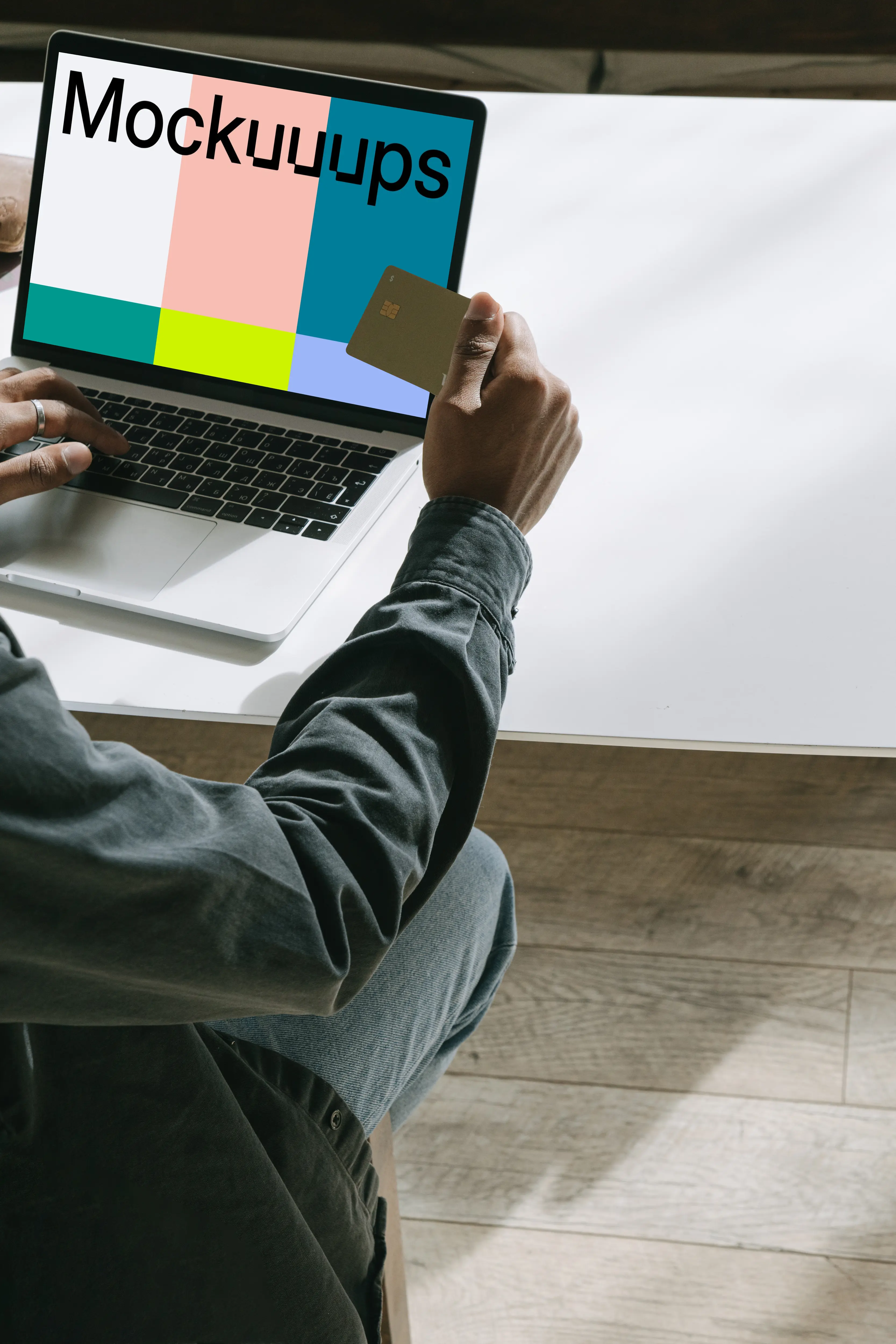 MacBook user holding a debit card in hand mockup.