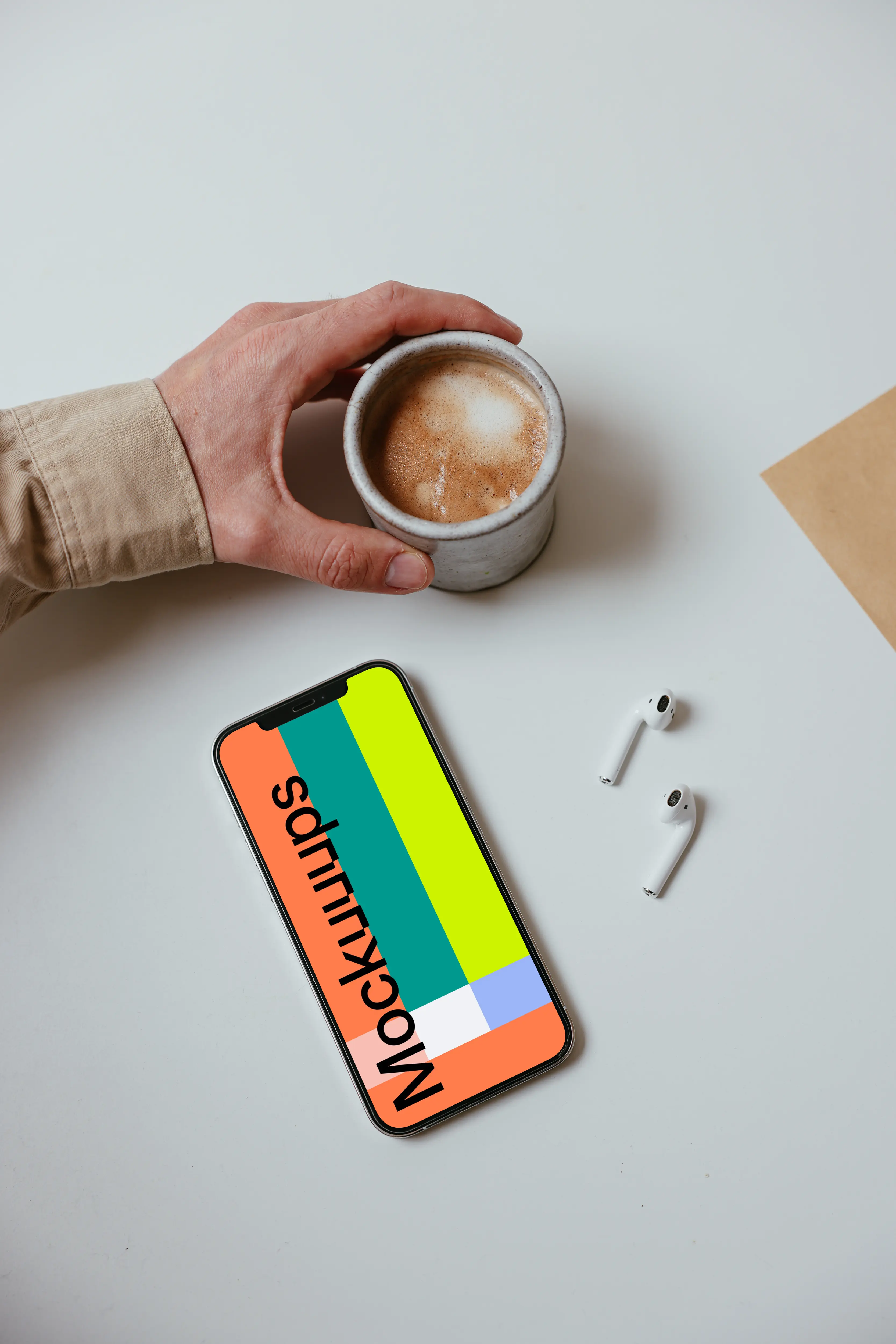 Minimal iPhone mockup on a table with a pair of Airpods and a cup of coffee