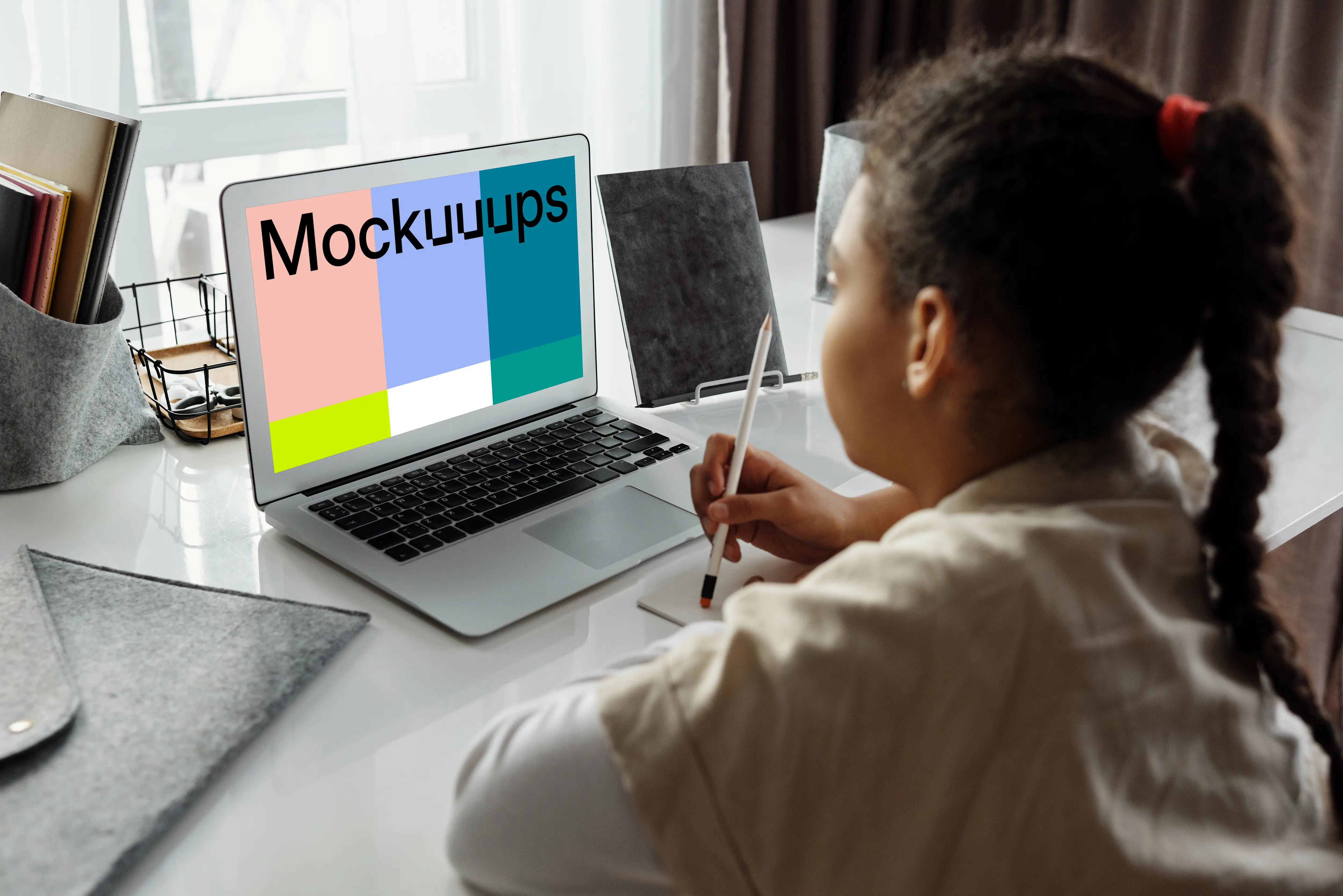Young girl using a MacBook Air with a pencil and a jotter mockup