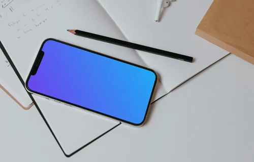 iPhone mockup on a table with books and a wireless keyboard by the side.