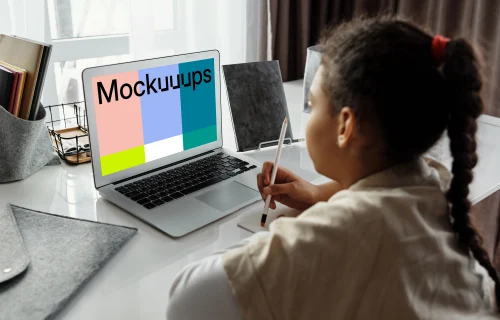 Young girl using a MacBook Air with a pencil and a jotter mockup