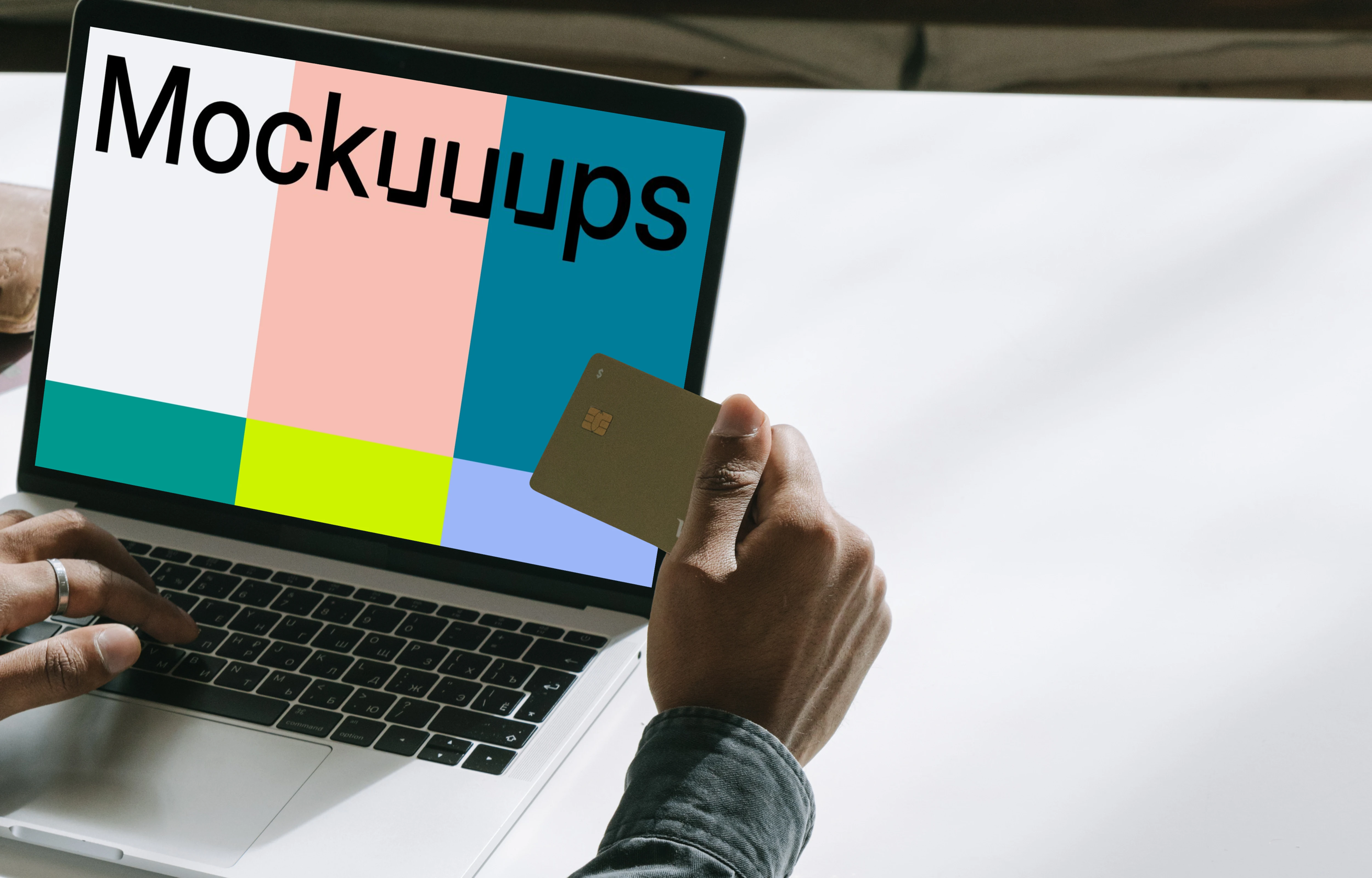MacBook user holding a debit card in hand mockup.