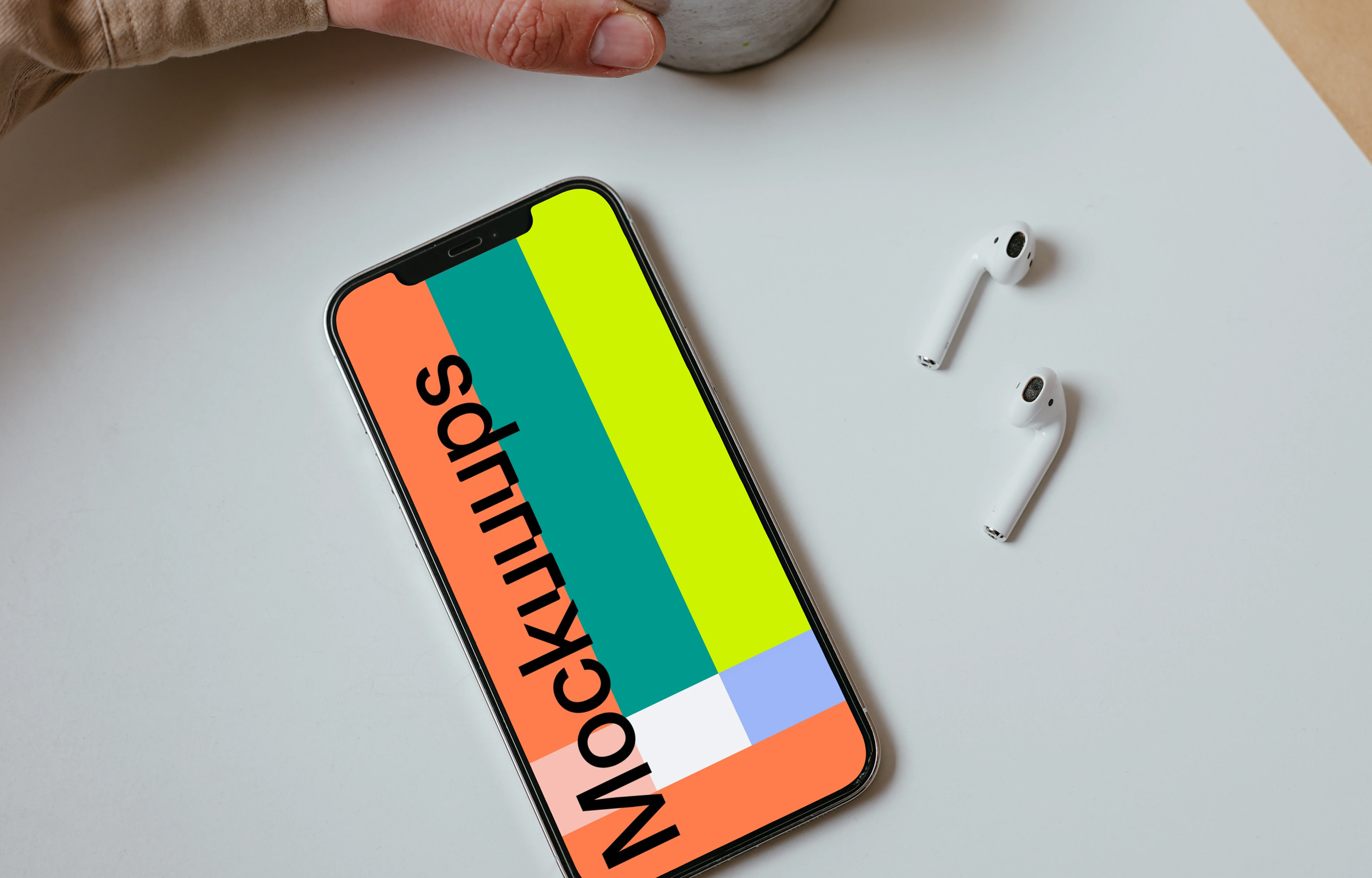 Minimal iPhone mockup on a table with a pair of Airpods and a cup of coffee