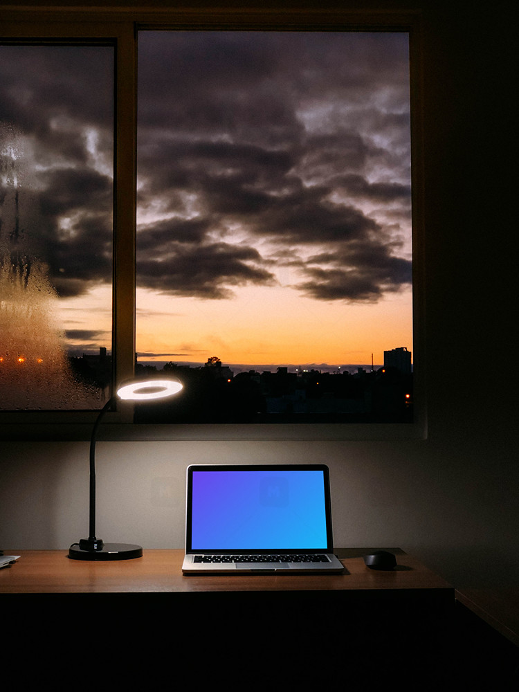 MacBook mockup at night with a reading lamp shining over it