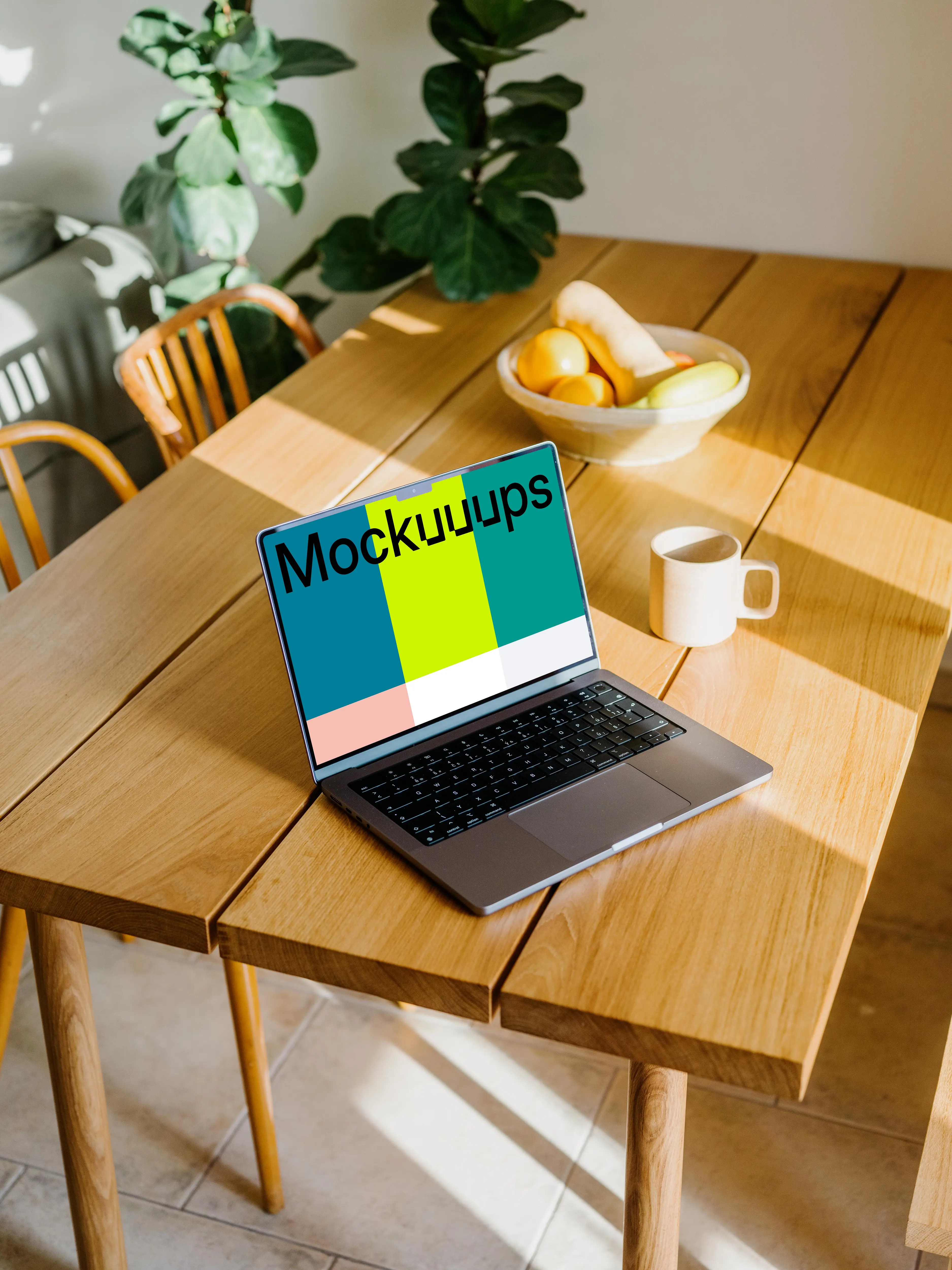 MacBook mockup beside a coffee mug and fruit basket mockup