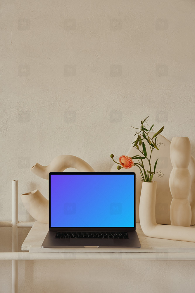 MacBook mockup on a peach colored table with a fancy flower vase