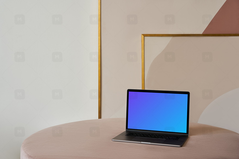 MacBook mockup on a table with a beautiful painting behind it