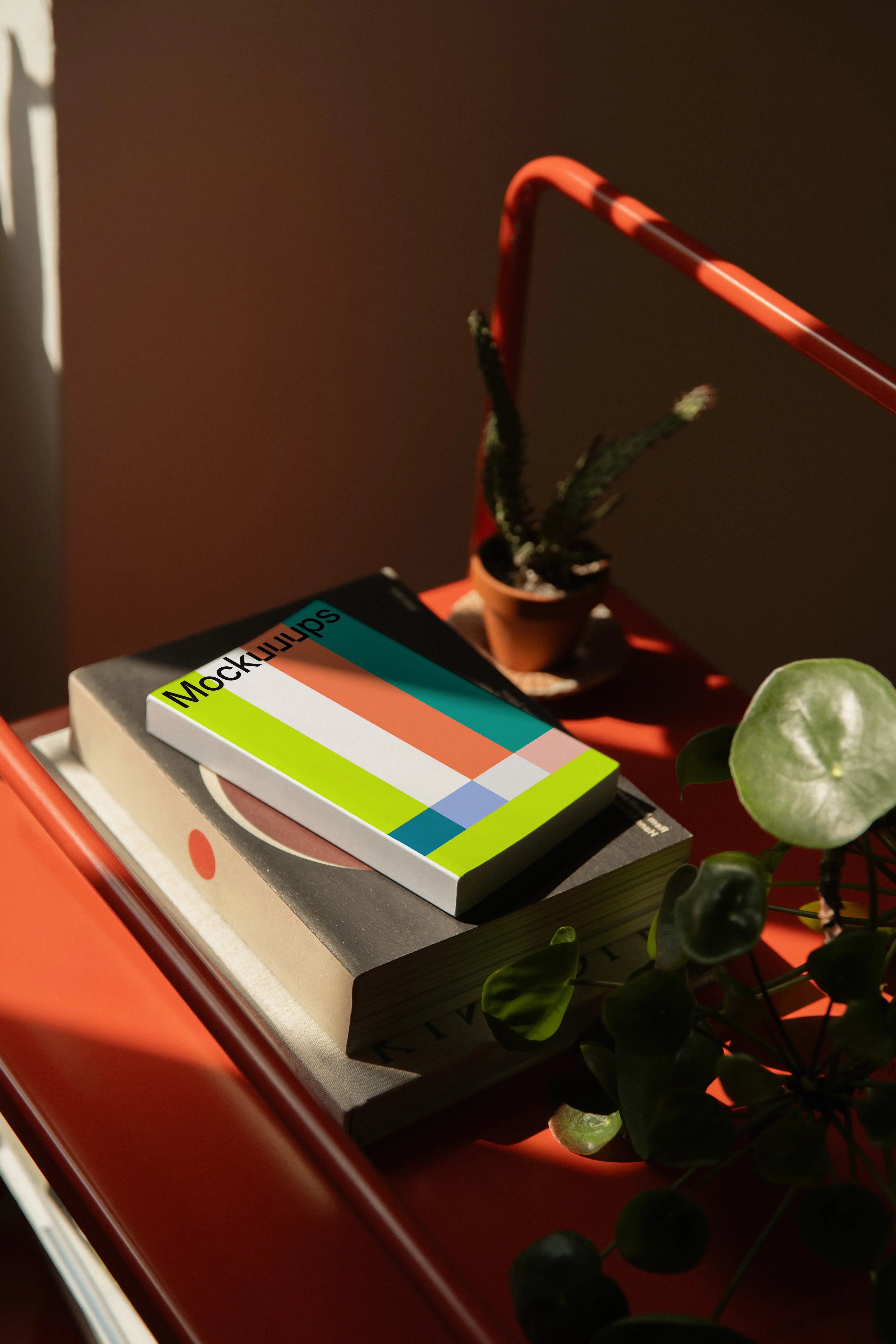 Paperback mockup on a red metal shelf with plants mockup